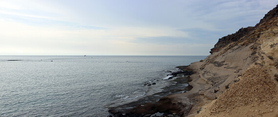 Panoramic view of a stretch of southern coast on the island of Tenerife with slopes and a view of the open sea in cloudy weather