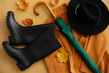 Umbrella, rubber boots, hat and cardigan on color background, closeup