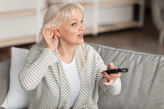 Hearing Problems. Mature woman watching television sitting on couch