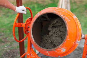 Cement slurry in an orange concrete mixer on a sunny summer day