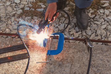 Man welds metal outdoors, close-up, beautiful sparks