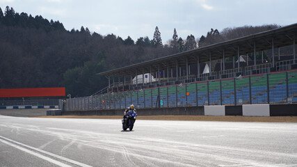 サーキットでホームストレートを走行する一台のバイク