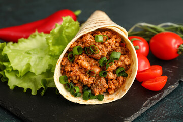 Slate plate with tasty burrito on dark background, closeup