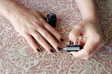 Middle age man painting nails in black colour at home in Madrid, Spain. Concepts of male makeup and self care