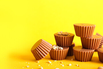 Tasty peanut butter cups on color background