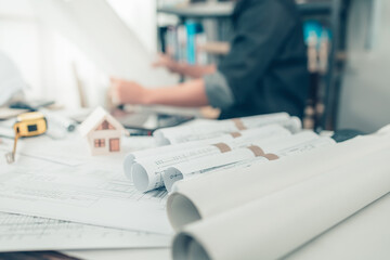 Architect rolls and plans on the table and architect engineer use pen drawing design working on bueprint. House planning design and construction concept.