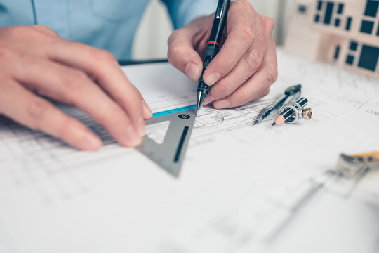 Architect engineer use pencil and triangular angle ruler  drawing design working on bueprint. House planning design and construction concept.