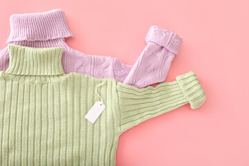 Knitted roll-neck sweaters and price tag on color background