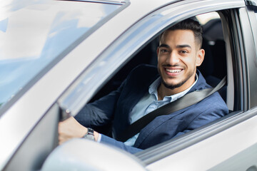 Cheerful arab businessman driving nice car, closeup