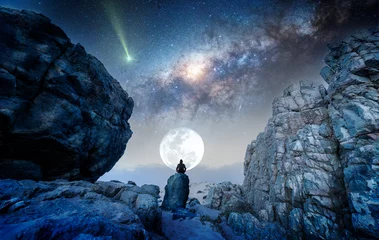 Foto auf Acrylglas Fantasielandschaft person on the rock outdoors meditating or praying at night under the Milky Way and Moon, back view