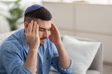 Fatigued upset jewish man suffering from headache massaging his temples