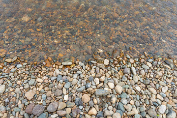 Smooth round pebble texture background. Pebble beach close-up, wet pebbles and dry pebbles. Background