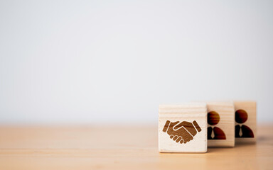 Hand shaking which print screen on wooden cube block  in front of human icon for business deal and agreement concept. - obrazy, fototapety, plakaty