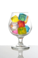 closeup brandy glass with multi colored plastic ice cubes 