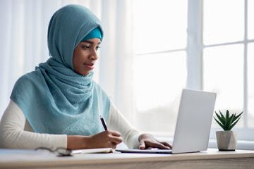 Online Learning Concept. Black Muslim Lady In Hijab Using Laptop At Home