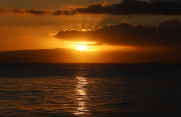 Fototapeta na wymiar Sun peeking over mountains at dawn. Monterey Bay, California in December. 