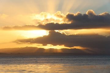 Beams of light through the clouds at sunrise over Monterey Bay, California, in December.