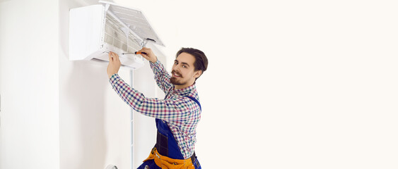Happy technician opens up modern wall mounted air conditioner to check it, do disinfection, or fix some troubles. White text copyspace banner background. Good AC maintenance and repair service concept