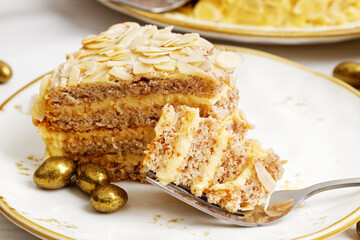 Piece of homemade cake with almond petals on white wooden table. Shallow focus.