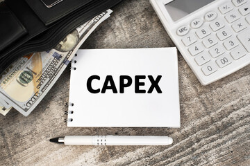 Capex is written on a white card. White calculator and black wallet with dollars on the table.