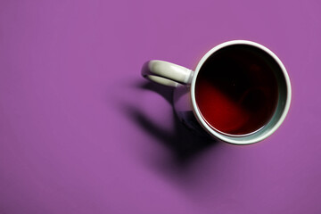 Photo of a cup with red liquid on a solid purple background