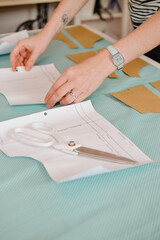 Obraz premium cut and sew children's and adult clothes for yourself or for sale. a woman to cut out the details of clothing from fabric. sew exclusive clothes to order or for yourself. sewing as a hobby or a job