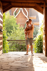 A father with a small son in his arms at a wooden gate