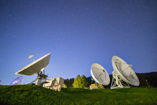 Group of communication satellite dishes at night with sky full of stars