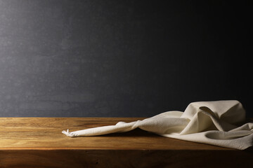 Natura morta con tessuto di lino bianco su tavola in legno, isolato su fondo scuro con spazio per testo