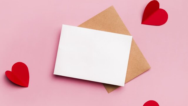 Mockup blank greeting gift card for valentines day. Composition with red hearts for Valentine's Day on a pale pink background. Flat lay. Love and relationships concept.
