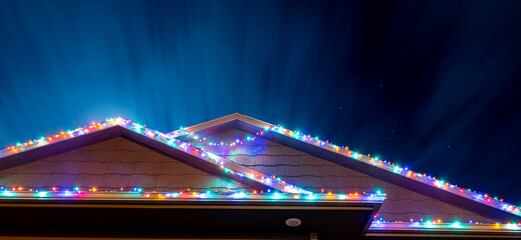 Sagging Christmas lights outdoors on a house that have come loose from the wind.