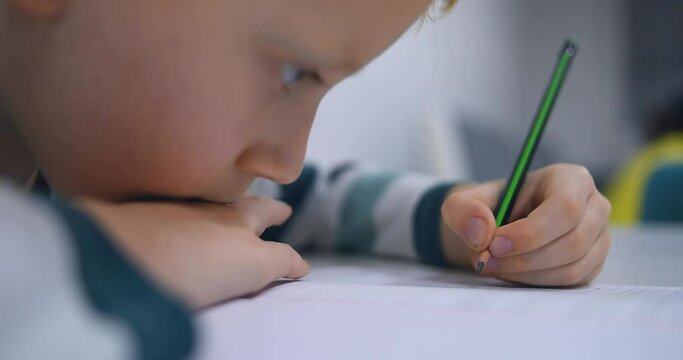 School boy practicing writing the alphabet at home. Boy child kid writing. Homework.