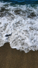 Aerial view of a wave crashing in a blue ocean.