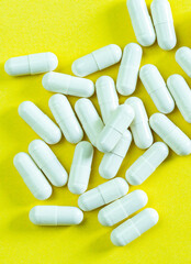 Pills and pill bottles on yellow background,Medical pills scattered from a white tube on a yellow background. Open mock-up Birth control pills