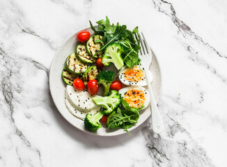 Vegetarian breakfast bowl - salad mixed vegetables, boiled egg, grilled zucchini, cheese on a light background, view over