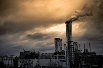The building of the old thermal power station under gloomy clouds. The smoking chimney of a large...