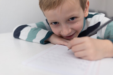 Naklejka premium School boy practicing writing the alphabet at home. Boy child kid writing. Homework.