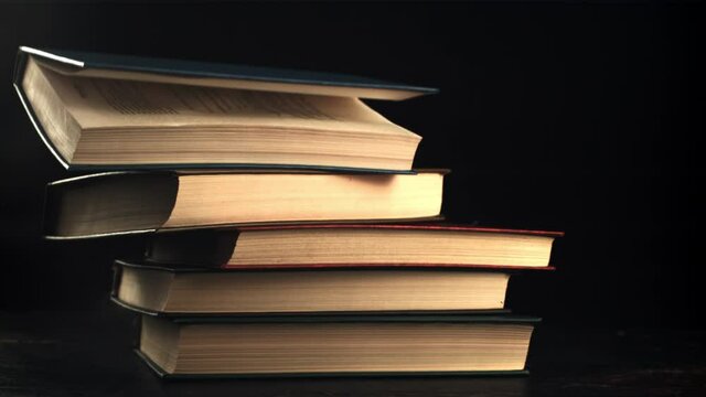 Books fall on the table. On a black background. Filmed is slow motion 1000 fps. High quality FullHD footage