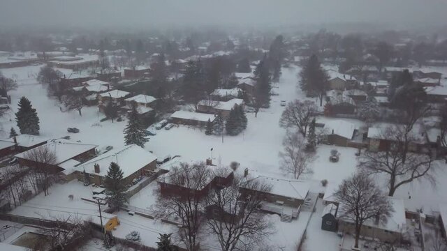 Descending aerial view into a snowy suburban neighborhood.