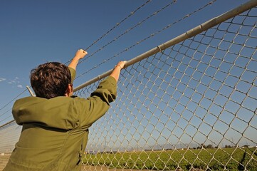 Teenage boy climbing chainlink fence with barbed wire on top, Camarillo, CA, USA