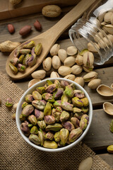 Bowl and wooden spoon with healthy nuts, pistachios on dark wood background