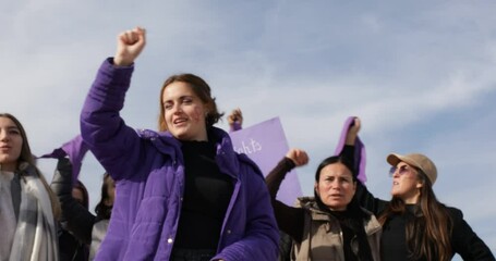 women standing raising fists and shouting slogans in feminist protest