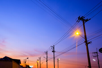 Silhouette of electric poles with power lines against colorful twilight sky background in low angle...
