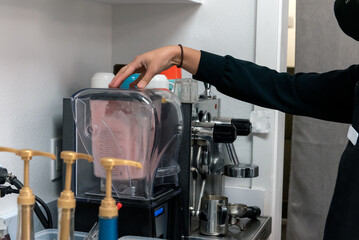 Hand holding the blender lid closed while mixing the boba smoothie ingredients for a ice cold beverage to drink
