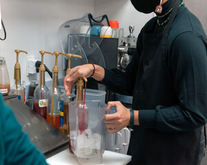 Pumping the colored flavor syrup into the iced blender to create a delicious boba smoothie to drink