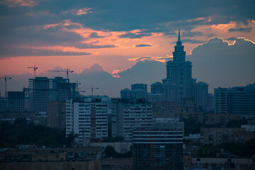 Fototapeta premium Pink and orange sunset with clouds and blue buildings and a cranes in the city. Moscow.