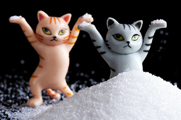Two funny toy kittens are having fun in a heap of white powder or snow. Winter rest and relaxation...