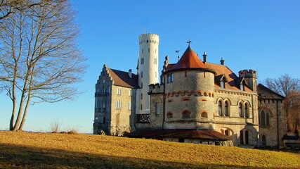 Eingang von Schloss Lichtenstein auf der  Schwäbischen Alb im Herbst unter blauem Himmel