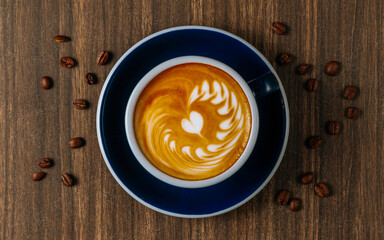 hot coffee latte art at morning time, and coffee beans in black coffee cup on dark wooden table top view