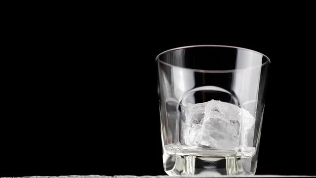 A man puts ice cubes in a whiskey glass. Preparation of an alcoholic cocktail.